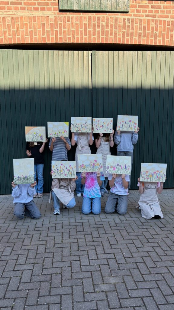 Kinder der Kreativschule zeigen ihre gemalten Blumenbilder