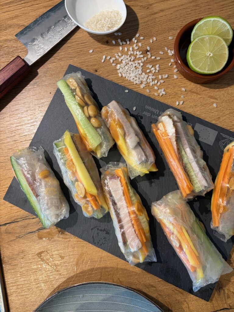 Sommerrollen mit Mango, Möhre und Gurke in Reihe auf Schiefer – Küchenparty Asia-Fingerfood in Kaarst
