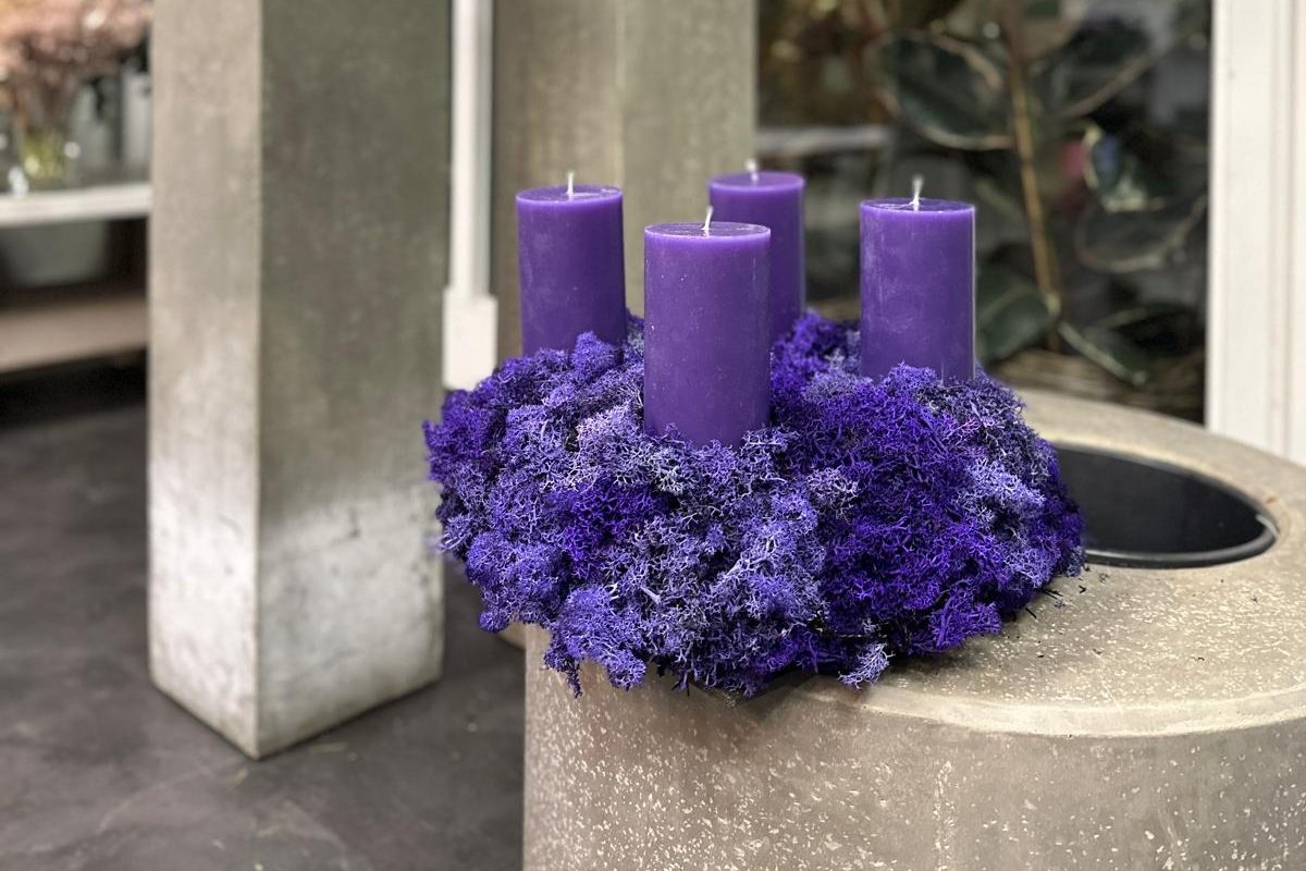 Adventskranz aus lila Islandmoos mit vier violetten Kerzen bei Selders